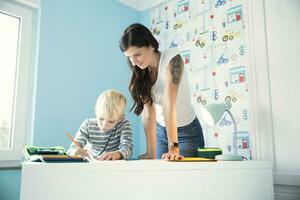 Mother helping son doing homework at desk photo