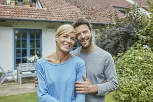 Portrait of smiling couple standing in front of their home photo