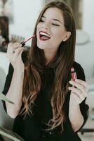 Portrait of happy young woman applying lipstick photo