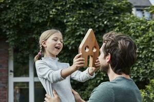 Father and daughter in garden of their home with house model photo