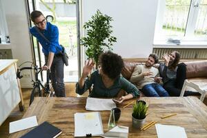 Coworkers waving at young man with bicycle arriving in modern office photo