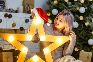 Happy young lady by the fireplace near the Christmas tree. New year concept. photo