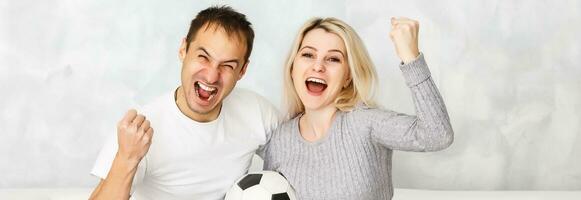 Young man watching football with his wife at home photo