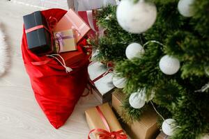 regalos en bolso mentira cerca un decorado Navidad o nuevo año árbol. rojo pantalones de Navidad regalos foto