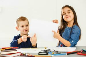 dos linda sonriente Niños de escuela con blanco sábana de papel en manos foto