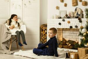 familia en Navidad víspera a chimenea. niños debajo Navidad árbol con regalo cajas decorado vivo habitación con tradicional fuego lugar. acogedor calentar invierno noche a hogar. foto