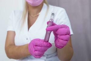 Mesotherapy And Microneedling Treatment. Closeup Real Female Dermatologist Holds Electric Microneedling Pen For Invasive Cosmetic Procedure Using Thin Needles. Microdermabrasion, Horizontal Plane photo