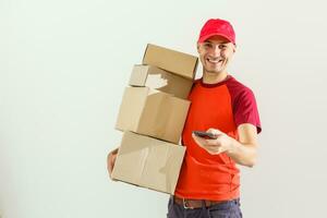 Photo of happy man from delivery service in red t-shirt and cap giving food order and holding boxes isolated over white background