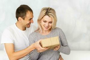 Man surprising his girlfriend with a gift on the couch at home in the living room photo