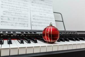 Christmas ball and lights on a classical piano keyboard, front view photo