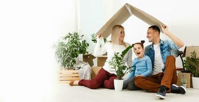 contento familia sentado en de madera piso. padre, madre y niño teniendo divertido juntos. Moviente casa día, nuevo hogar y diseño interior concepto foto