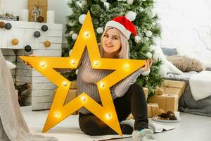 Portrait of happy woman in santa hat holding big golden star. photo