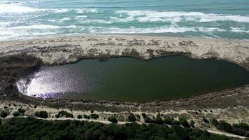 Marina di Vecchiano Pisa Tuscany Italy aerial view of the small lake in front of the sea with waves crashing video