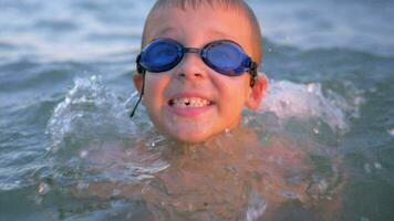 de bonne humeur garçon dans des lunettes de protection baignade dans le mer video