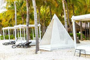 Palapa thatched roofs palms parasols sun loungers beach resort Mexico. photo