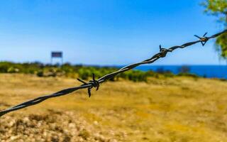 Nature beach and desert behind barbed wire fence and chains. photo