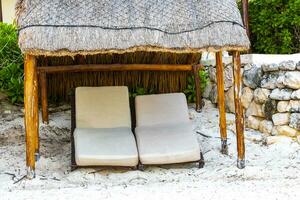 Palapa thatched roofs palms parasols sun loungers beach resort Mexico. photo