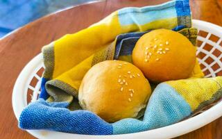 Delicious round buns with sesame seeds on wooden table Mexico. photo