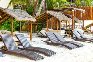 Palapa thatched roofs palms parasols sun loungers beach resort Mexico. photo