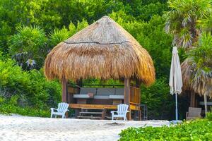 Palapa thatched roofs palms parasols sun loungers beach resort Mexico. photo