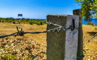 Nature beach and desert behind barbed wire fence and chains. photo
