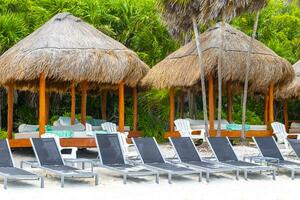 Palapa thatched roofs palms parasols sun loungers beach resort Mexico. photo