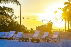 Palapa thatched roofs palms parasols sun loungers beach resort Mexico. photo