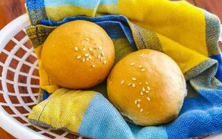 Delicious round buns with sesame seeds on wooden table Mexico. photo