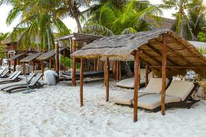 Palapa thatched roofs palms parasols sun loungers beach resort Mexico. photo