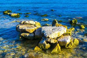 Stones rocks corals turquoise green blue water on beach Mexico. photo