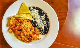 tortilla mexicana huevos frijoles negros papas nachos en plato blanco. foto