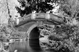 Beautiful old stone bridge with railing over clean river in preserve photo