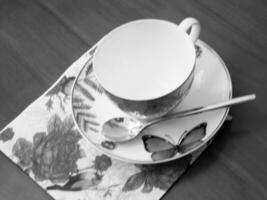 Empty coffeecup standing on wooden table for dark tasty coffee photo