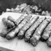 Barbecue with fiery Bavarian sausages on grill in garden outdoors photo