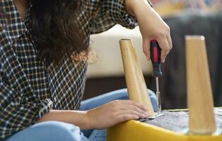 Asian Woman self repairs furniture renovation using equipment to diy repairing furniture sitting on the floor at home photo