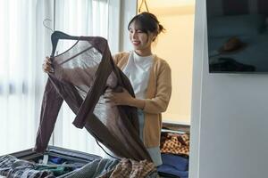 Asian girl preparing vacation choosing clothes with wardrobe in bedroom before holidays trip photo