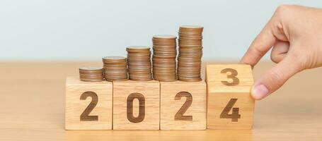 flipping 2023 to 2024 year block with Coins stack. Money, Budget, tax, investment, financial, savings and New Year Resolution concepts photo