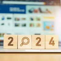 2024 block with magnifying glass icon against laptop background. Hiring, recruitment, job, jobless SEO, Search Engine Optimization and New Year concepts photo