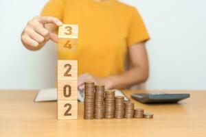 flipping 2023 to 2024 year block with Coins stack. Money, Budget, tax, investment, financial, savings and New Year Resolution concepts photo
