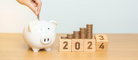 Happy New Year with piggy bank and flipping 2023 change to 2024 block. Resolution, Goals, Plan, Action, Money Saving, Retirement fund, Pension, Investment and Financial concept photo