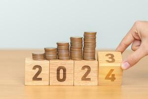 flipping 2023 to 2024 year block with Coins stack. Money, Budget, tax, investment, financial, savings and New Year Resolution concepts photo