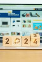 2024 block with magnifying glass icon against laptop background. Hiring, recruitment, job, jobless SEO, Search Engine Optimization and New Year concepts photo