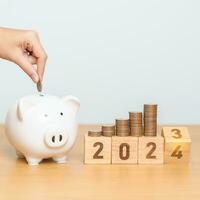 Happy New Year with piggy bank and flipping 2023 change to 2024 block. Resolution, Goals, Plan, Action, Money Saving, Retirement fund, Pension, Investment and Financial concept photo