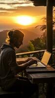 Man typing on computer at sunrise photo