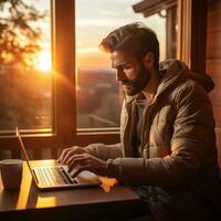 Man typing on computer at sunrise photo