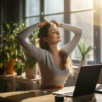 Woman stretching at desk with sunlight streaming in photo