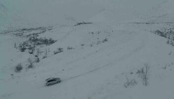 carro em pesado Nevado estrada dentro montanhas, aéreo Visão video