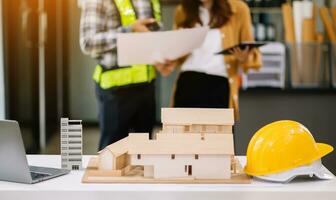 escritorio de ingeniero con papel de objeto y tableta con trabajo en equipo de ingenieros borrosos que trabajan duro para consultar sobre su proyecto de construcción. foto