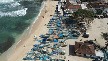 aereo fuco Visualizza di gli ombrelli, Barche e persone avendo vacanza a il spiaggia nel Yogyakarta Indonesia video