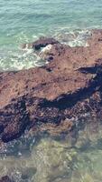 Vertical video fo turquoise blue water and rocks. Sea, beach.